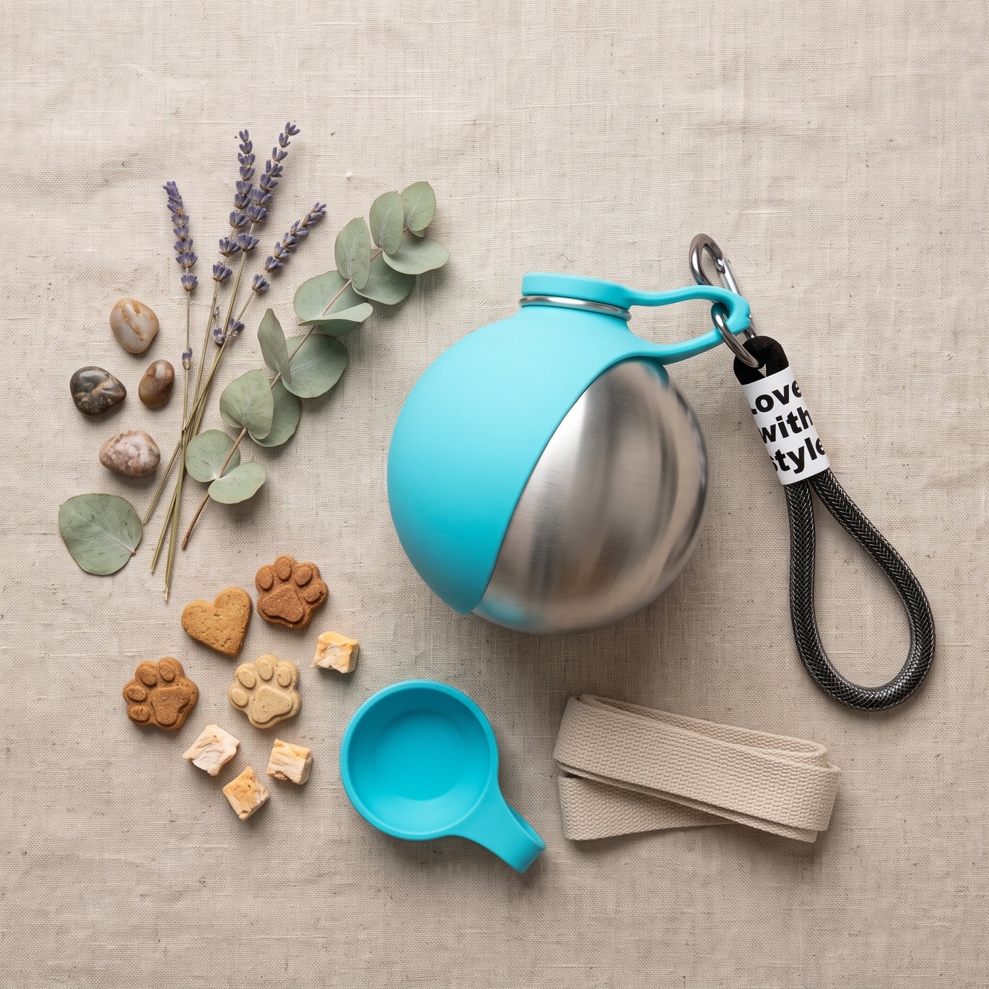 Portable Dog Water Dispenser in teal, flat lay with lavender, eucalyptus, treats, collapsible cup and leash strap