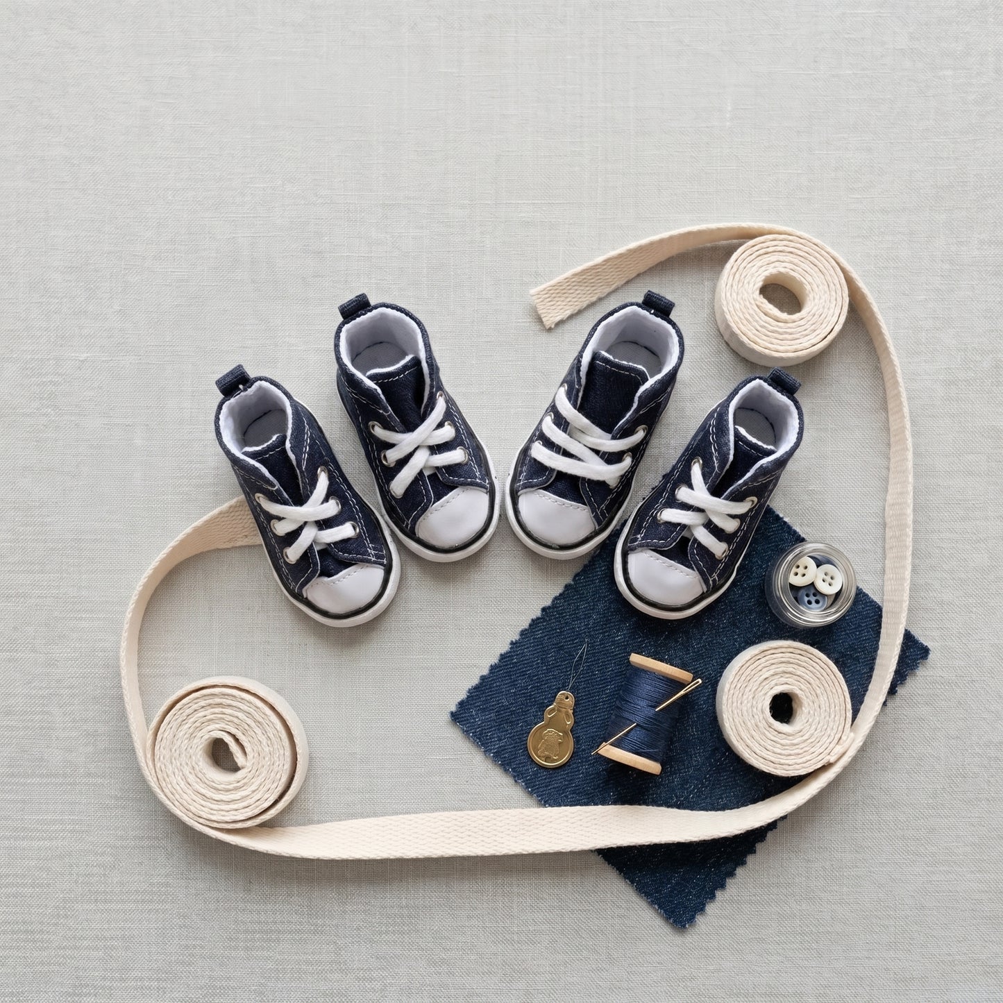 Waterproof Denim Pet Sneakers in navy, flat lay with cotton webbing, denim swatch, buttons, thread and needle